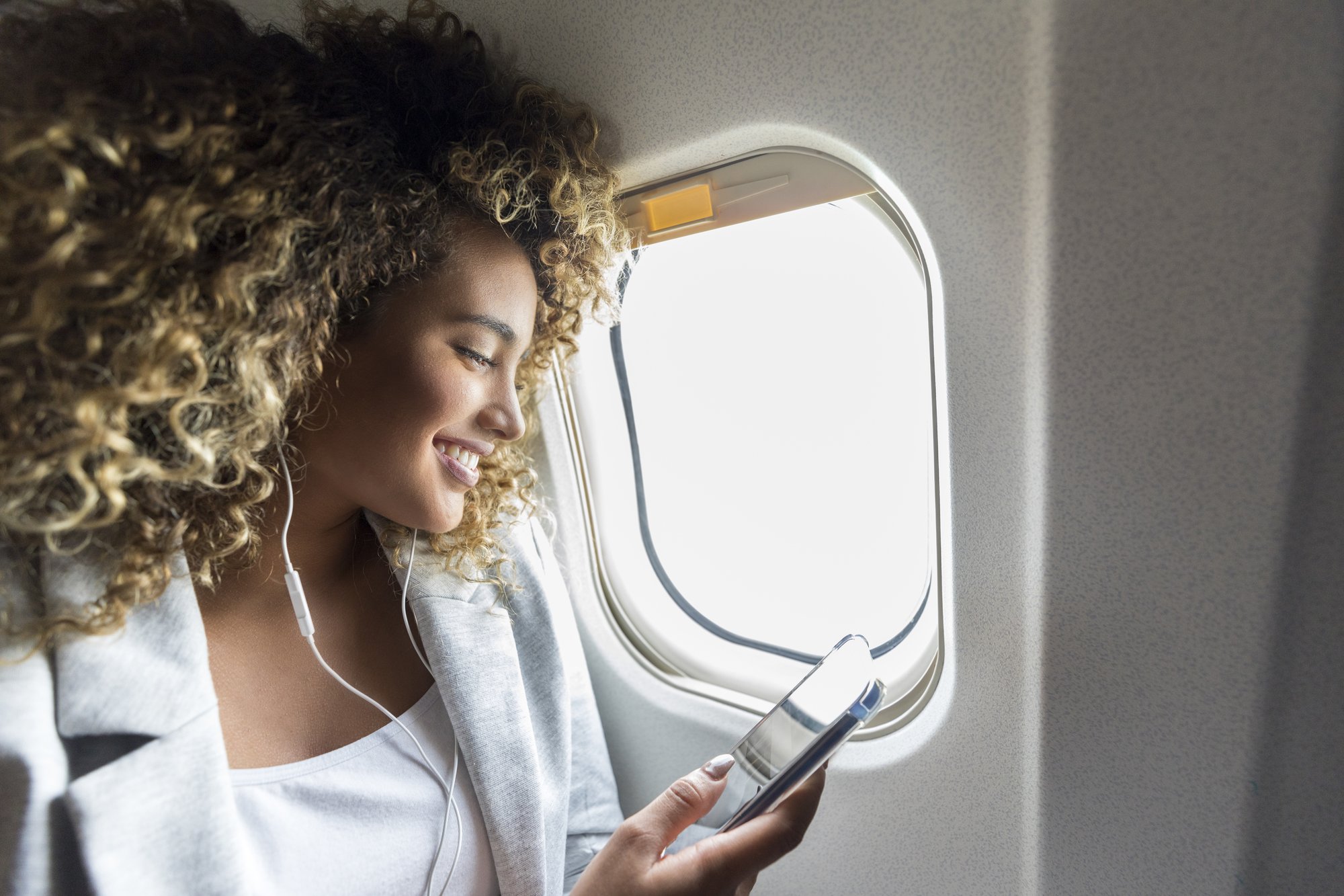 Woman looking at smartphone near airplane window