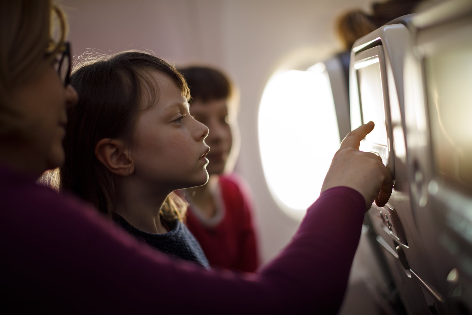 Woman on an airplane touches the in-flight entertainment screen