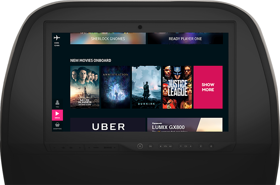 Airplane seat-back entertainment screen showing movie options and advertisements