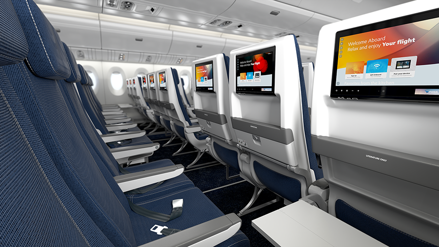 Interior of an economy class airplane cabin with blue seats and seatback entertainment screens