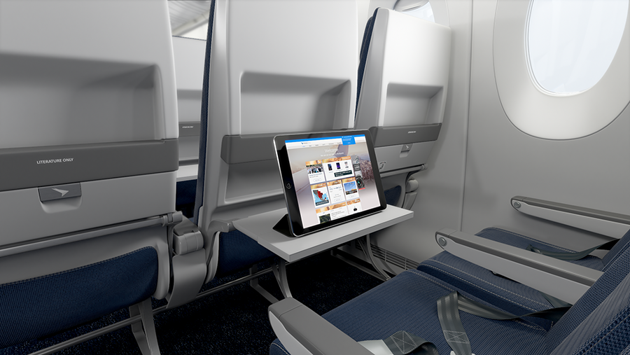 Airplane economy class seats with a deployed tray table holding a tablet